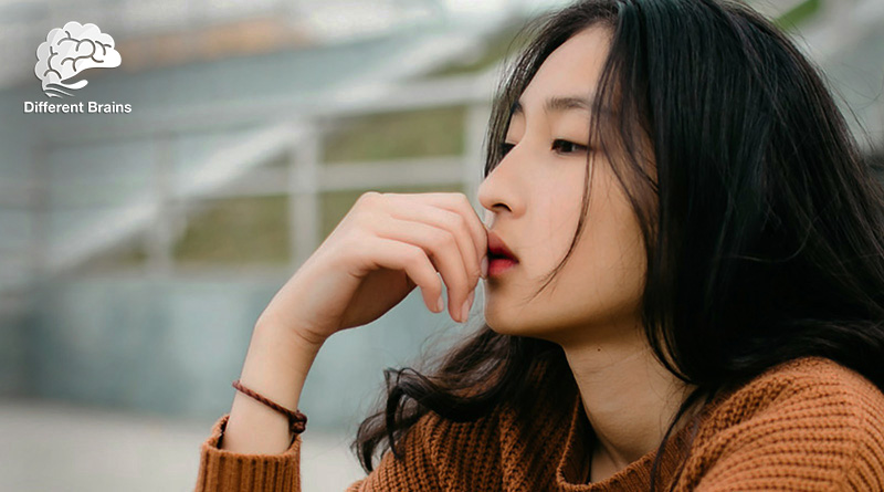 A woman holds her hand to her chin while looking pensive