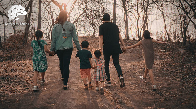 A family of six walk through a wooded area