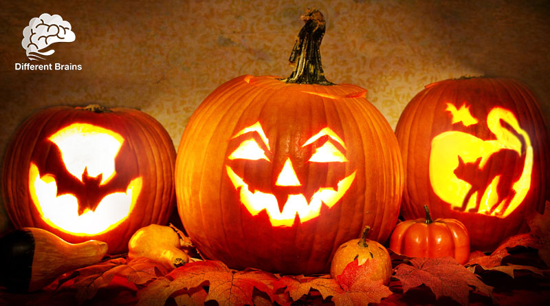 Three jack-o-lanterns sit on a bed of orange leaves.
