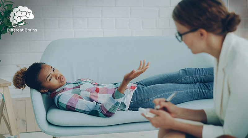 A woman lays on a couch talking to her therapist.