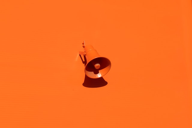 An orange loudspeaker on an orange background.