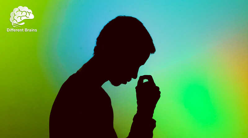 A person in silhouette hangs their head forward and reaches for their temples