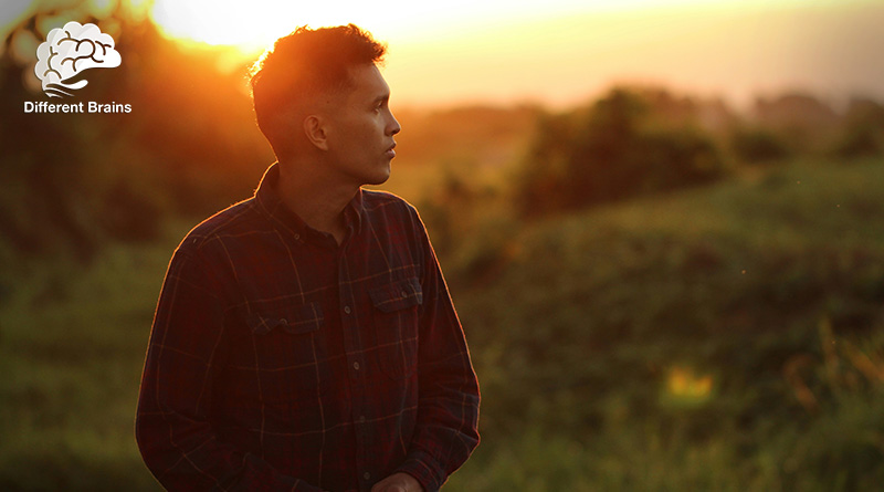 A man looks contemplatively off to the distance during a sunrise.